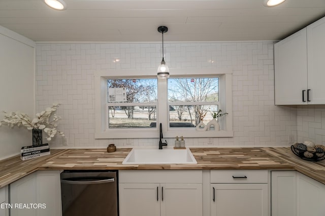 kitchen with sink, tasteful backsplash, wooden counters, decorative light fixtures, and white cabinets