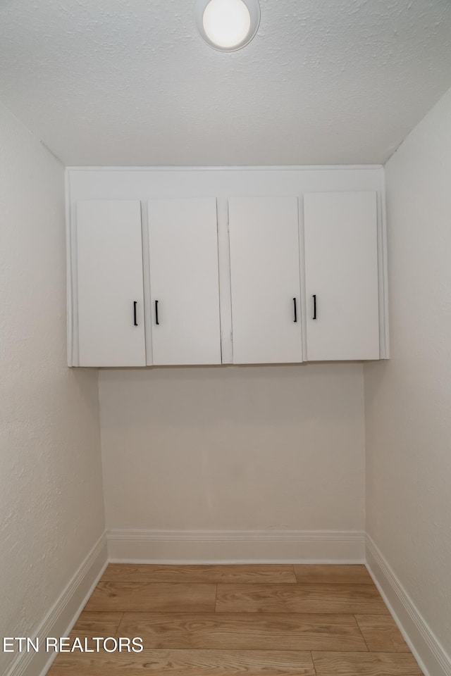 laundry room featuring a textured ceiling and light wood-type flooring