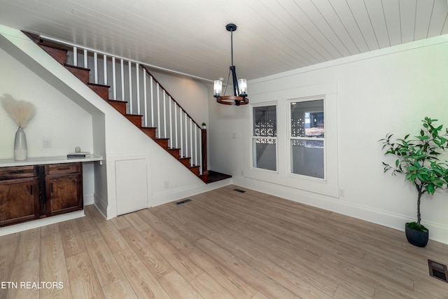 interior space featuring an inviting chandelier, crown molding, and light hardwood / wood-style floors