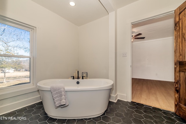 bathroom featuring vaulted ceiling, tile patterned floors, and a tub to relax in