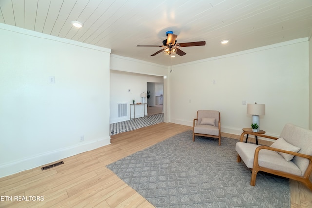 living area featuring hardwood / wood-style flooring, ornamental molding, wooden ceiling, and ceiling fan