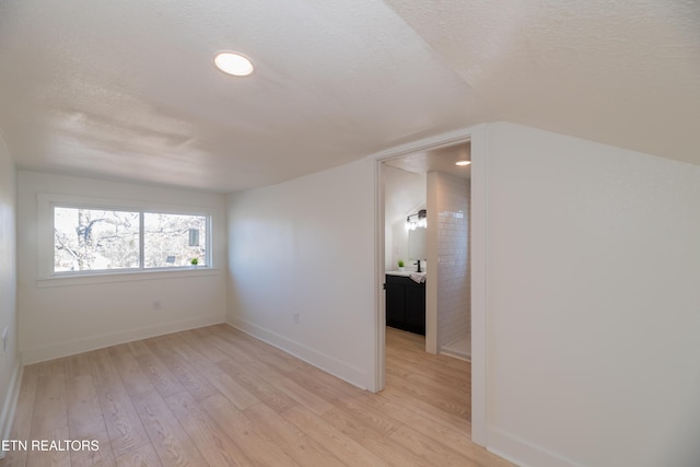 spare room with a textured ceiling and light wood-type flooring