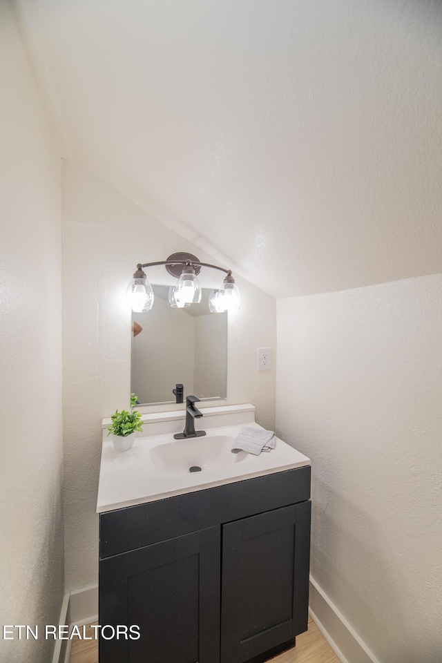 bathroom featuring vanity, vaulted ceiling, and wood-type flooring