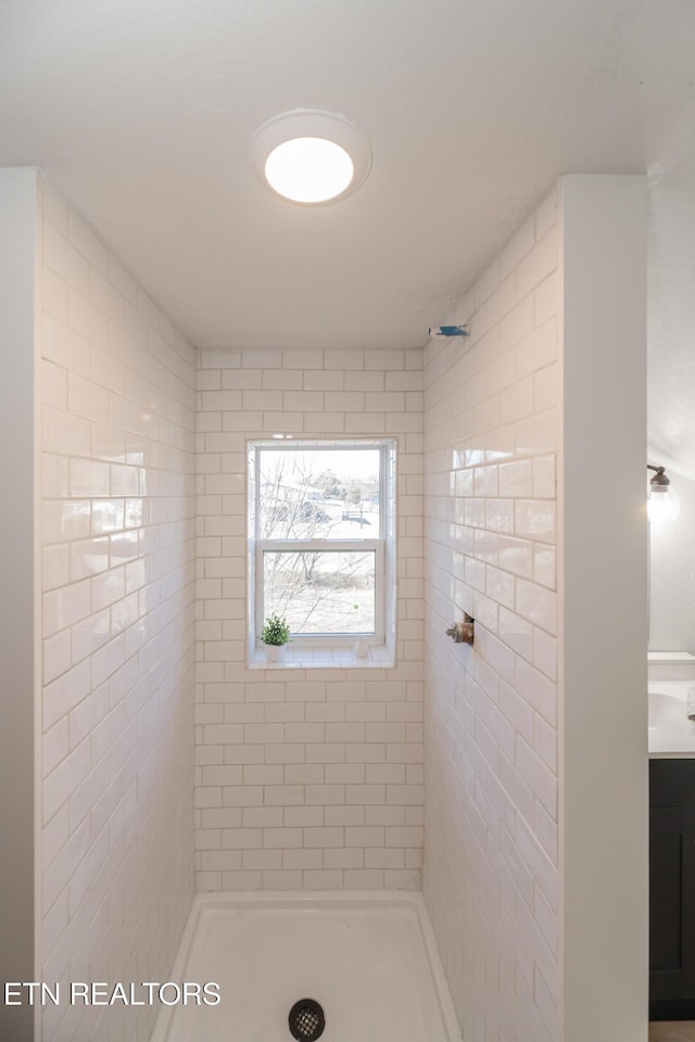 bathroom with vanity and a tile shower