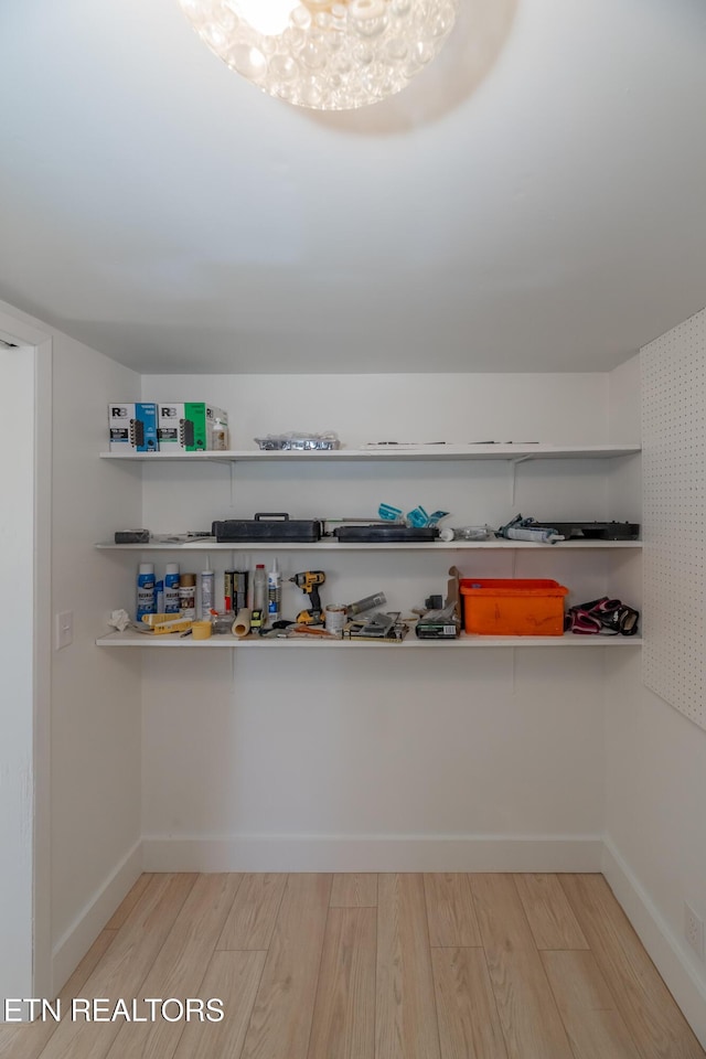 spacious closet featuring an inviting chandelier and light hardwood / wood-style floors