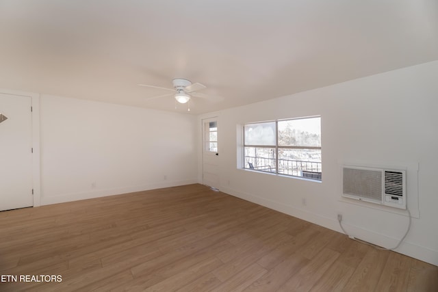 unfurnished room with ceiling fan, a wall unit AC, and light wood-type flooring