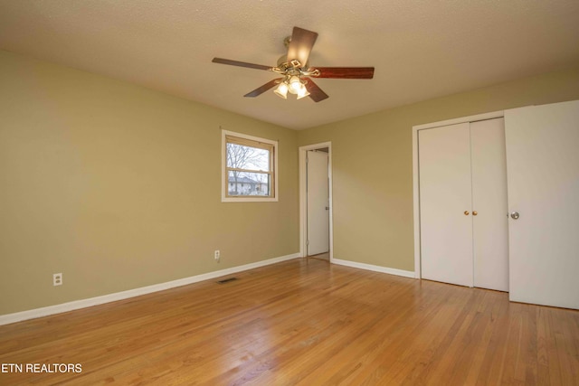 unfurnished bedroom with a textured ceiling, a closet, ceiling fan, and light wood-type flooring