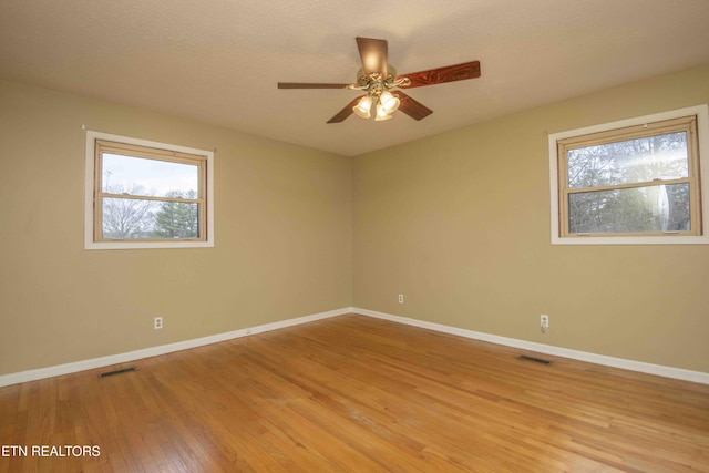 unfurnished room with a healthy amount of sunlight, a textured ceiling, ceiling fan, and light hardwood / wood-style flooring