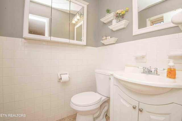 bathroom featuring vanity, toilet, and tile walls