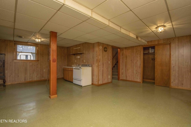 basement featuring wooden walls, sink, and a drop ceiling