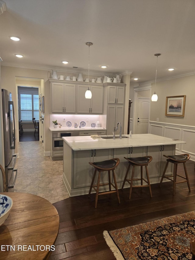 kitchen with appliances with stainless steel finishes, decorative light fixtures, sink, and a center island with sink