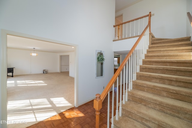 stairway featuring parquet flooring and a towering ceiling