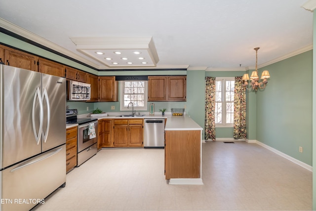 kitchen featuring sink, appliances with stainless steel finishes, hanging light fixtures, a wealth of natural light, and ornamental molding