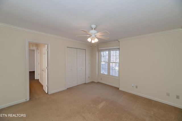 unfurnished bedroom with crown molding, light colored carpet, ceiling fan, and a closet