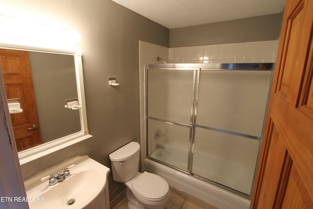 full bathroom with vanity, a textured ceiling, shower / bath combination with glass door, and toilet