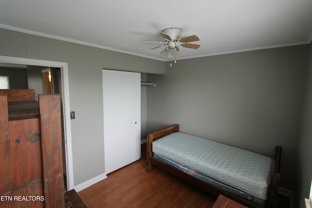 bedroom with crown molding, dark hardwood / wood-style floors, ceiling fan, and a closet