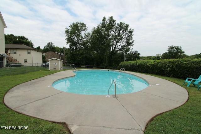 view of pool featuring a yard and a shed