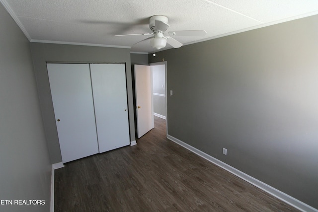 unfurnished bedroom with ceiling fan, crown molding, dark wood-type flooring, a textured ceiling, and a closet