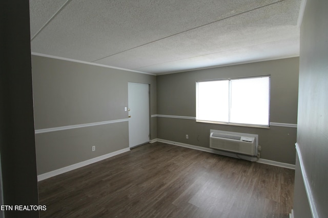 empty room featuring crown molding, dark wood-type flooring, a wall unit AC, and a textured ceiling