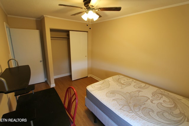 bedroom featuring crown molding, ceiling fan, wood-type flooring, and a closet