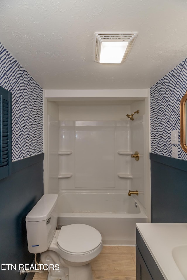 full bathroom with wood-type flooring, vanity,  shower combination, toilet, and a textured ceiling