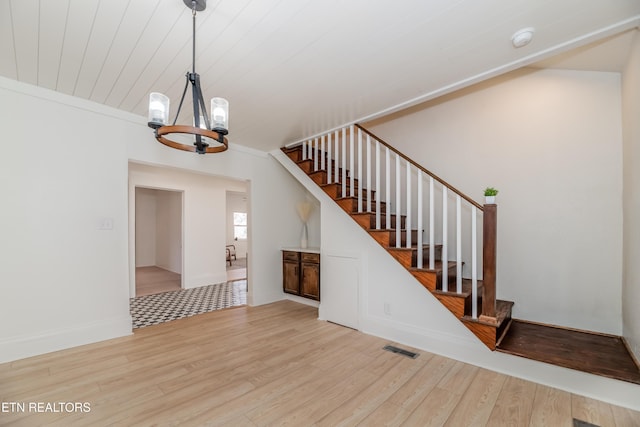 stairway with wood-type flooring, a notable chandelier, and wood ceiling