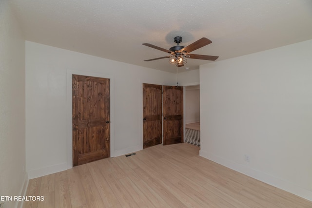 unfurnished bedroom featuring ceiling fan, a textured ceiling, and light wood-type flooring