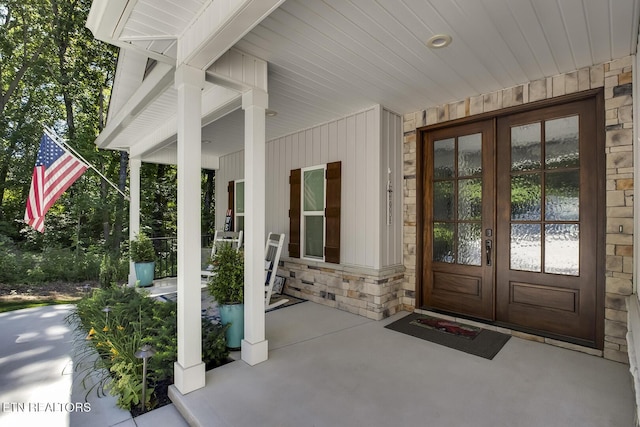 view of exterior entry featuring french doors and covered porch