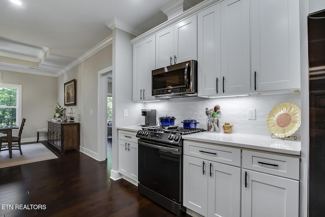 kitchen with dark wood-type flooring, white cabinetry, ornamental molding, appliances with stainless steel finishes, and backsplash