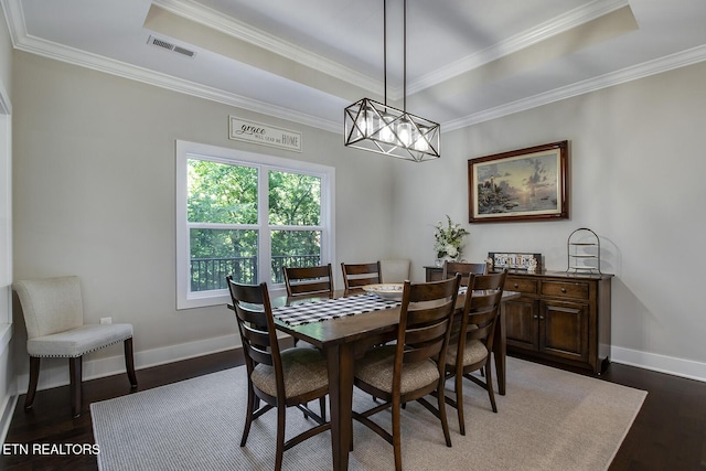 dining room featuring crown molding, a notable chandelier, a tray ceiling, and dark hardwood / wood-style floors