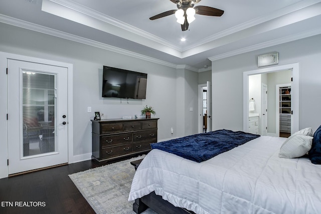 bedroom featuring crown molding, ensuite bath, ceiling fan, dark hardwood / wood-style floors, and a tray ceiling