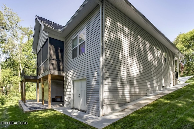 view of side of property featuring a yard, a patio area, and a sunroom