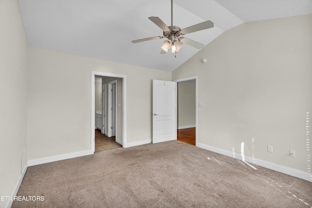 unfurnished bedroom featuring ceiling fan, lofted ceiling, light colored carpet, and ensuite bath