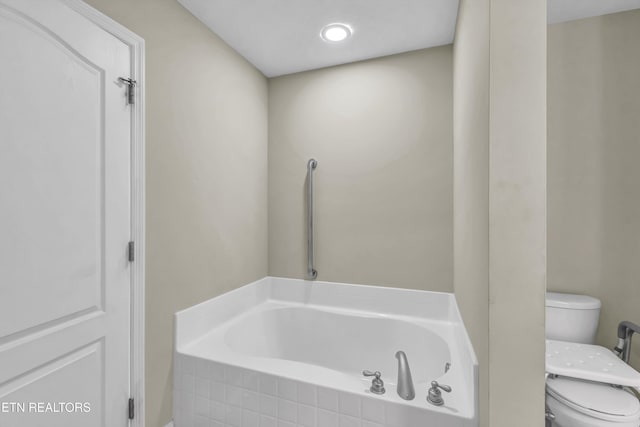 bathroom featuring a relaxing tiled tub and toilet