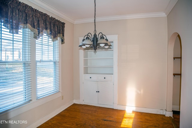 unfurnished dining area featuring an inviting chandelier, crown molding, and dark hardwood / wood-style floors