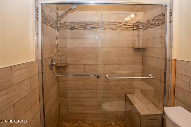 bathroom featuring a shower with shower door and toilet