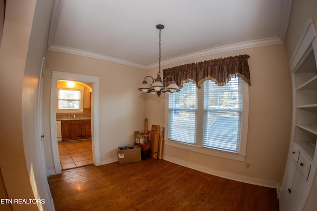 unfurnished dining area with an inviting chandelier, sink, crown molding, and hardwood / wood-style floors