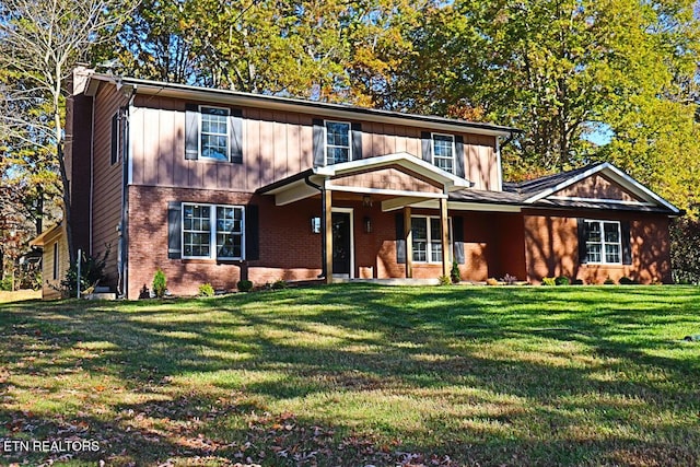 view of front facade with a front yard, board and batten siding, and brick siding