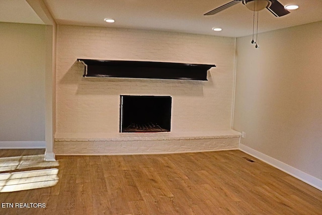 unfurnished living room with a fireplace, visible vents, a ceiling fan, wood finished floors, and baseboards