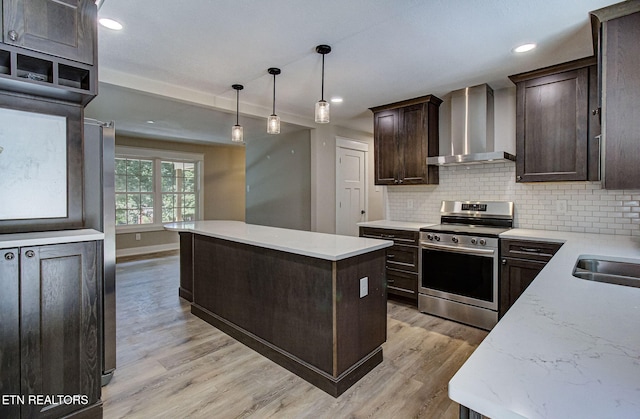 kitchen featuring tasteful backsplash, wall chimney exhaust hood, stainless steel electric range oven, a kitchen island, and pendant lighting