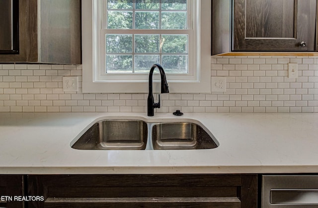 interior details featuring light stone countertops, dark brown cabinets, sink, and backsplash