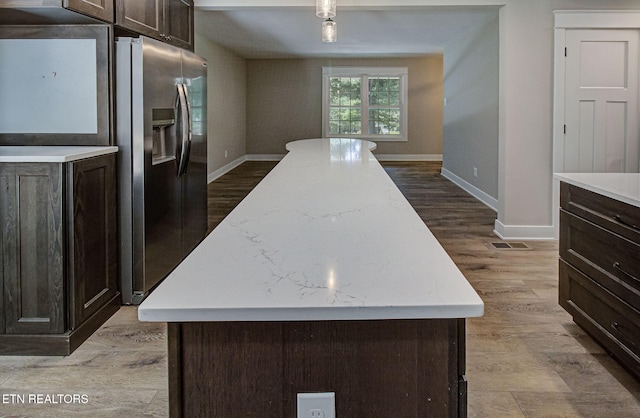 kitchen with light hardwood / wood-style flooring, dark brown cabinets, stainless steel fridge, and a kitchen island