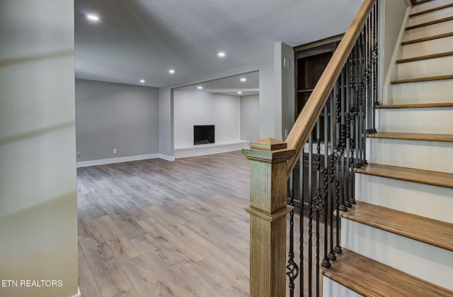 staircase with hardwood / wood-style flooring, a fireplace, and built in shelves