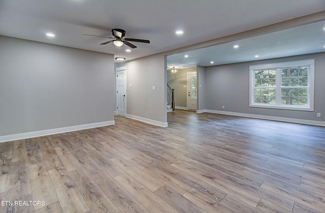 spare room with recessed lighting, a ceiling fan, baseboards, light wood-style floors, and stairway