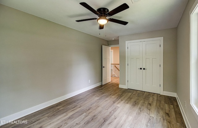 unfurnished bedroom featuring light wood finished floors, ceiling fan, baseboards, and a closet