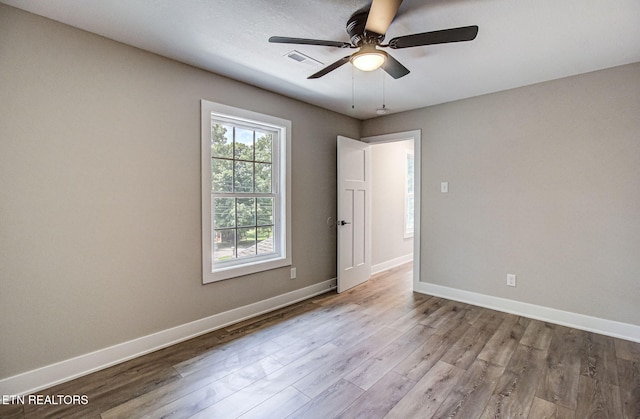 unfurnished room featuring ceiling fan, light wood-type flooring, visible vents, and baseboards