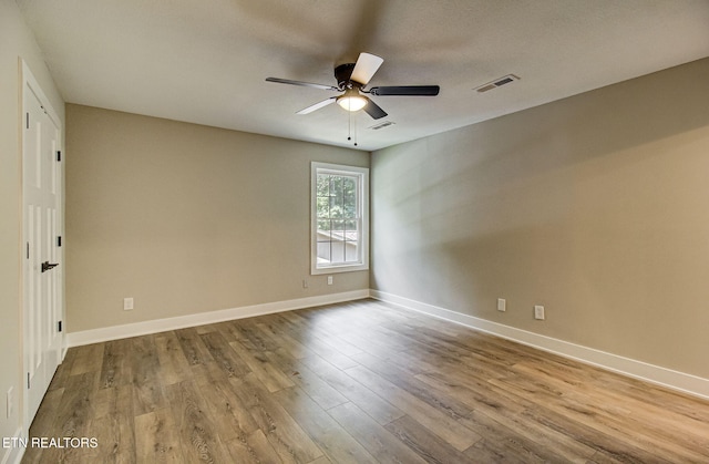 unfurnished room featuring ceiling fan, light wood-type flooring, visible vents, and baseboards