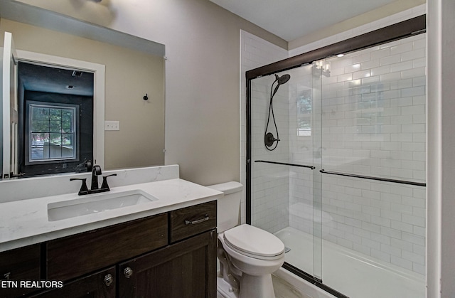 bathroom with vanity, a shower with door, and toilet