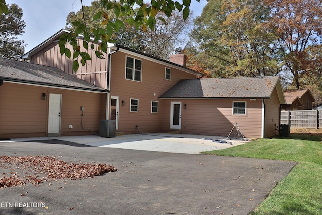 back of property featuring central AC, a yard, a chimney, and fence