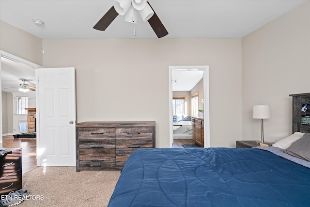 bedroom featuring ceiling fan, ensuite bath, and multiple windows